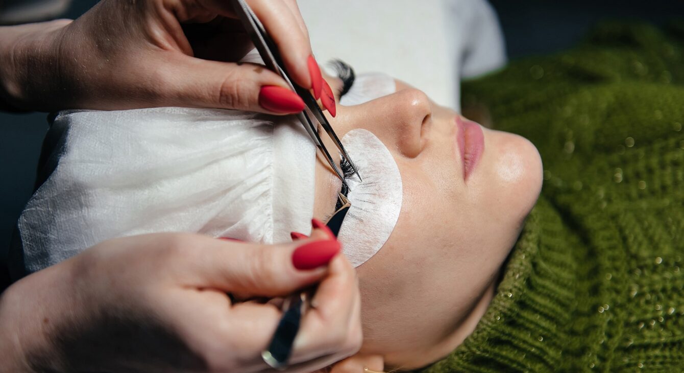 eyelash-extension-process-closeup-portrait-young-girl-woman-with-long-thick-eyelashes-eyes-closed-hand-cosmetologist-adding-more-eyelashes-her